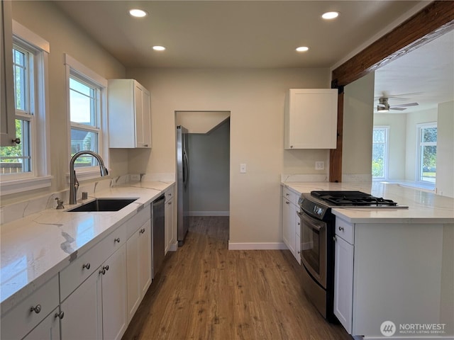 kitchen with stainless steel appliances, a sink, recessed lighting, white cabinets, and a peninsula