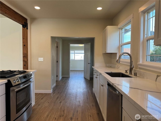 kitchen featuring stainless steel appliances, a sink, white cabinets, light stone countertops, and recessed lighting