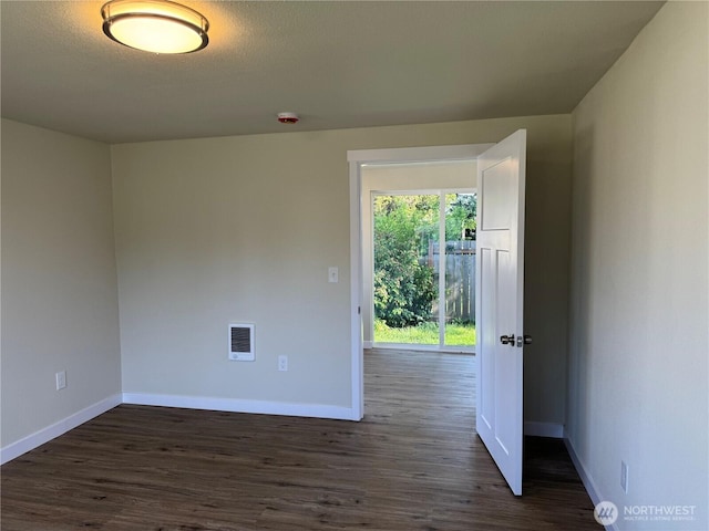 unfurnished room with baseboards, dark wood-style floors, and a smoke detector