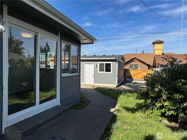 view of property exterior with fence and an outbuilding