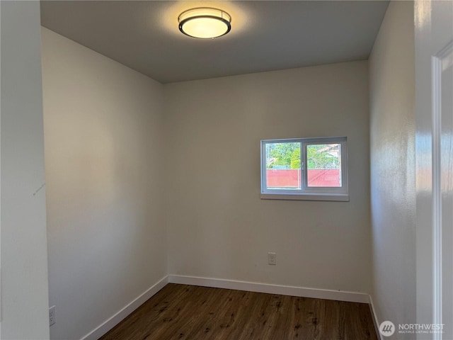 unfurnished room featuring baseboards and dark wood-type flooring