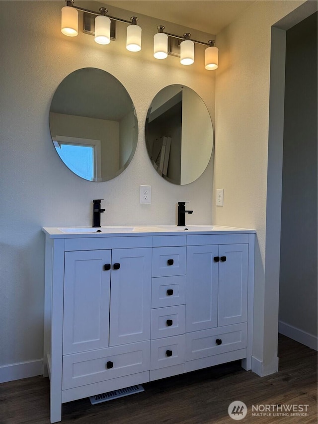 full bath with baseboards, wood finished floors, and double vanity
