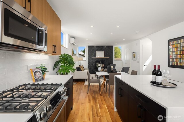 kitchen featuring brown cabinetry, appliances with stainless steel finishes, light wood-type flooring, light countertops, and recessed lighting