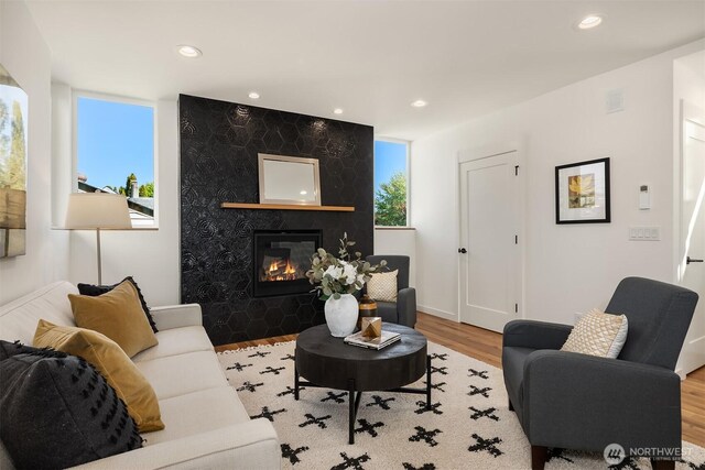living room featuring recessed lighting, wood finished floors, visible vents, and a large fireplace