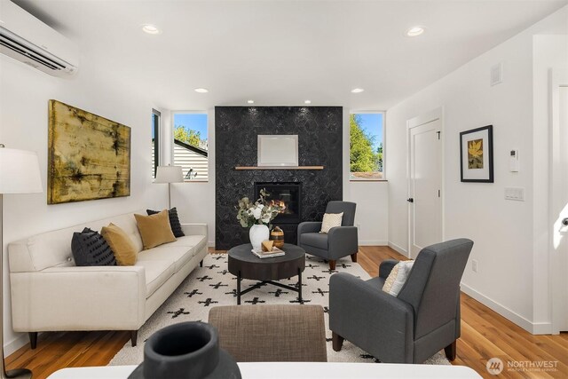 living room with a premium fireplace, recessed lighting, a wall unit AC, wood finished floors, and visible vents