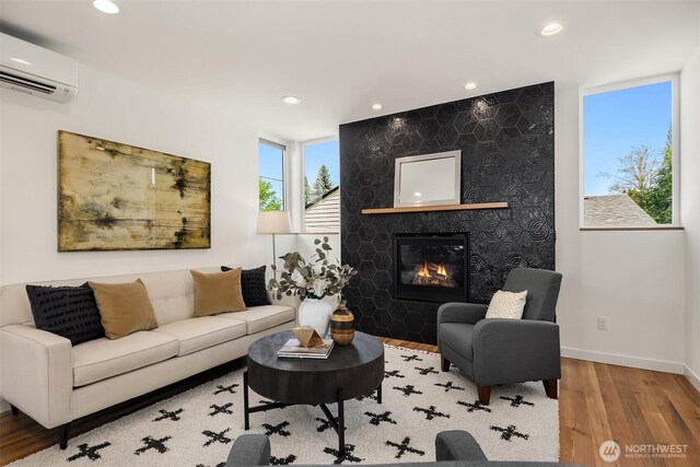 living area featuring recessed lighting, a stone fireplace, wood finished floors, and a wall mounted air conditioner