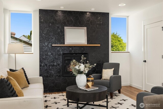 living room with recessed lighting, baseboards, a glass covered fireplace, and wood finished floors