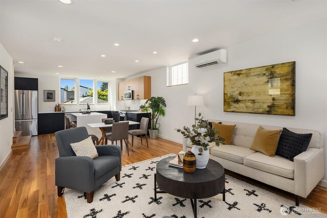 living area with baseboards, light wood finished floors, recessed lighting, and a wall mounted air conditioner