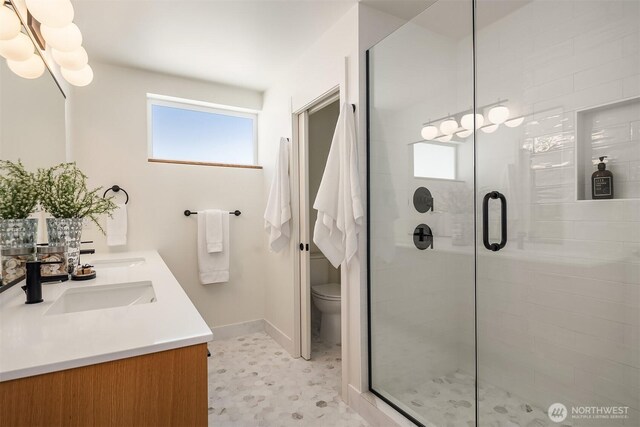 bathroom with a sink, baseboards, a shower stall, and toilet