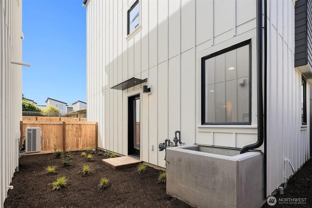 exterior space with board and batten siding, fence, and central AC unit