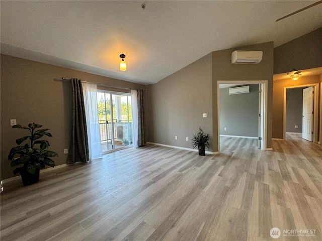 empty room with baseboards, light wood-style flooring, a wall mounted AC, and vaulted ceiling
