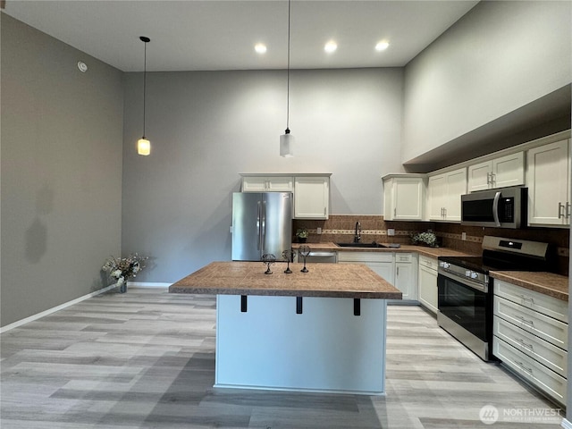 kitchen with a sink, light wood finished floors, tasteful backsplash, and stainless steel appliances