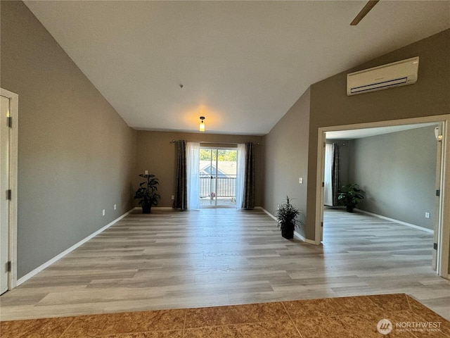 interior space with a ceiling fan, vaulted ceiling, baseboards, an AC wall unit, and light wood-style flooring