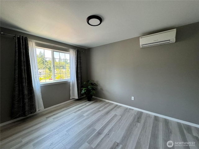 unfurnished room with baseboards, wood finished floors, and a wall mounted air conditioner