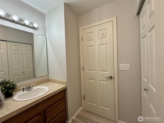 bathroom featuring baseboards, vanity, and wood finished floors