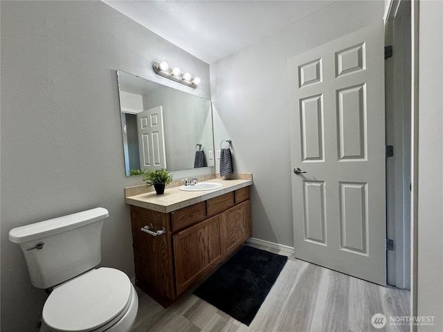 half bath featuring vanity, wood finished floors, and toilet