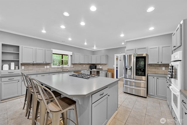 17132 156th Ln SE, Yelm, WA 98597 - kitchen featuring decorative backsplash, ornamental molding, a kitchen island, a sink, and appliances with stainless steel finishes