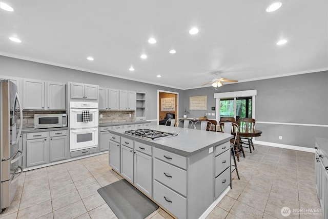 17132 156th Ln SE, Yelm, WA 98597 - kitchen featuring light tile patterned flooring, ceiling fan, a center island, stainless steel appliances, and ornamental molding