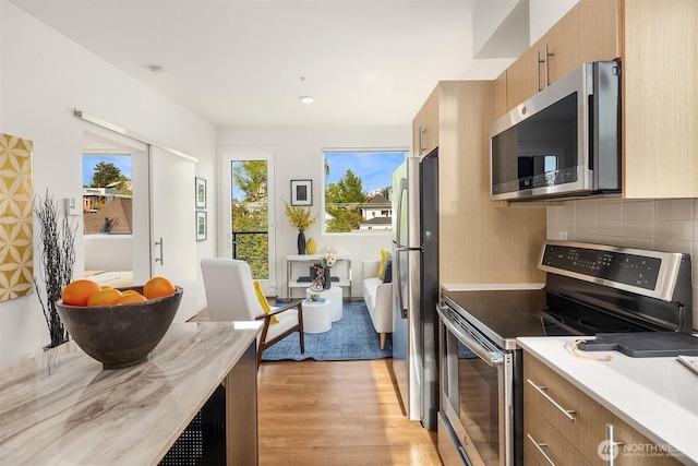 121 12th Ave E Unit 506, Seattle, WA 98102 - kitchen with appliances with stainless steel finishes, light wood-type flooring, decorative backsplash, and brown cabinets