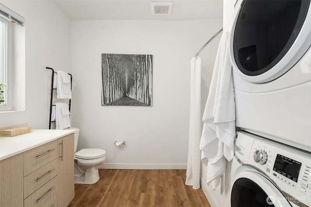 121 12th Ave E Unit 506, Seattle, WA 98102 - bathroom featuring stacked washer / dryer, wood finished floors, toilet, baseboards, and a shower with shower curtain