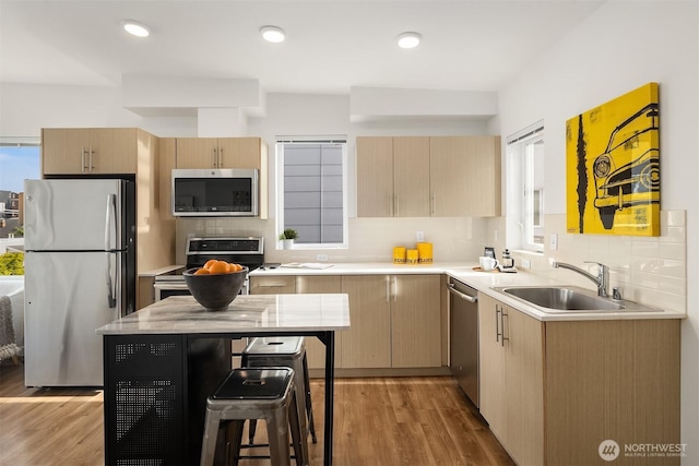 121 12th Ave E Unit 506, Seattle, WA 98102 - kitchen featuring stainless steel appliances, a sink, light brown cabinets, light countertops, and decorative backsplash