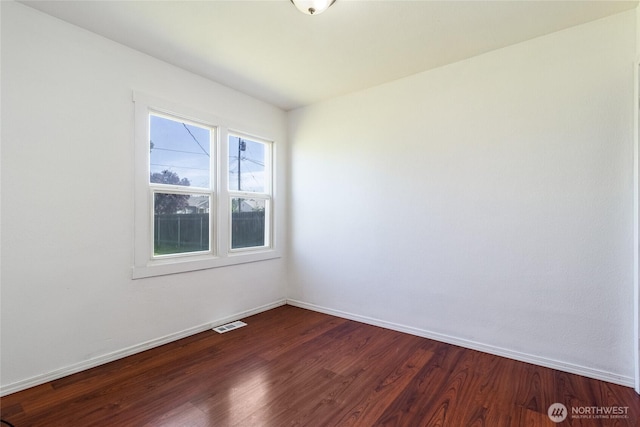 unfurnished room featuring dark wood finished floors, visible vents, and baseboards