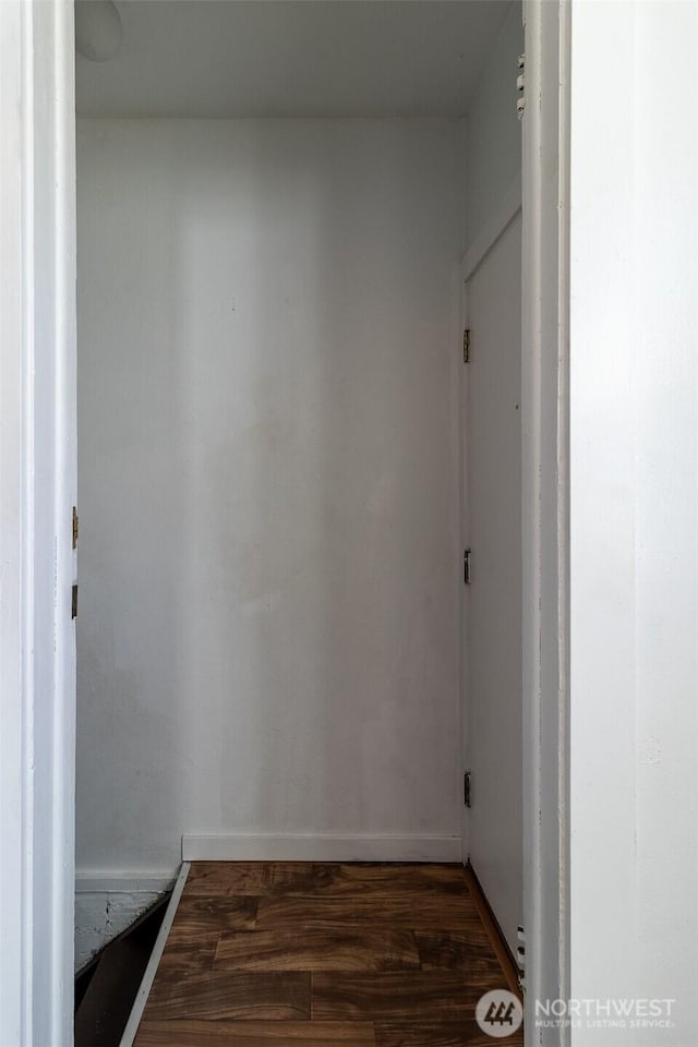 hallway with dark wood-style flooring and baseboards