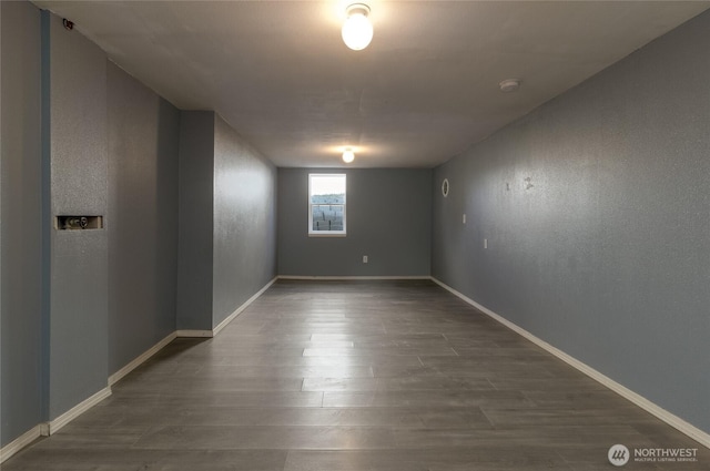 spare room with baseboards and dark wood-type flooring