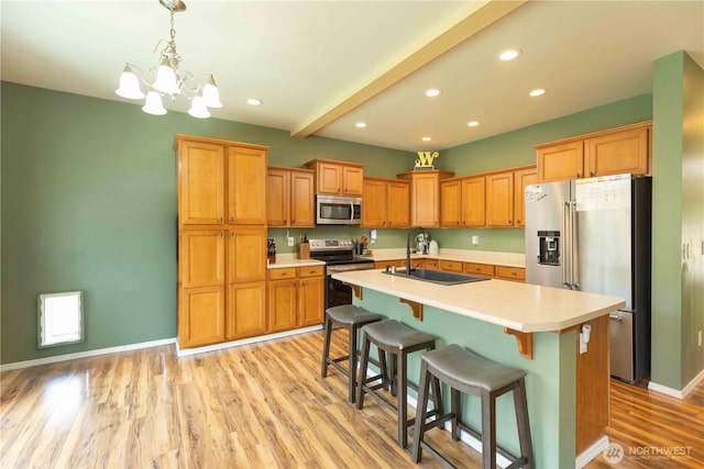 kitchen with stainless steel appliances, a sink, light countertops, light wood-style flooring, and recessed lighting