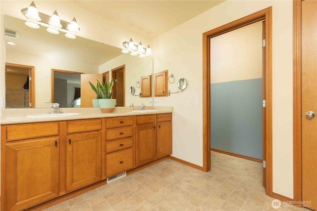 bathroom with baseboards, double vanity, and tile patterned floors