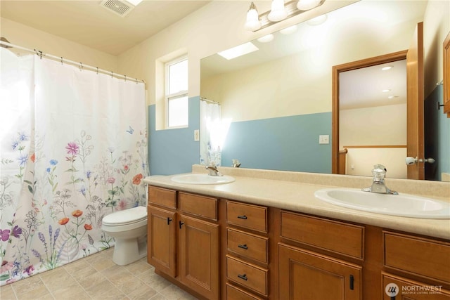 bathroom with double vanity, toilet, and curtained shower