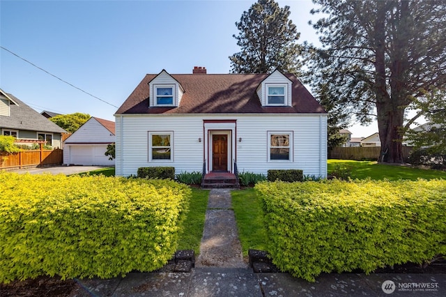 new england style home with a detached garage, fence, a chimney, and an outdoor structure