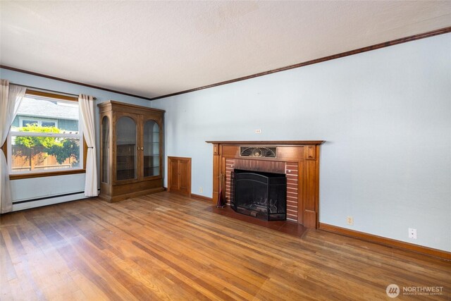 unfurnished living room with crown molding, wood finished floors, baseboard heating, and a fireplace