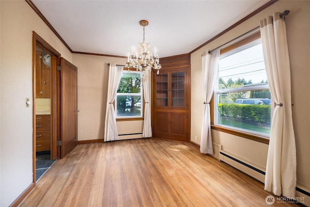 unfurnished dining area featuring plenty of natural light, an inviting chandelier, ornamental molding, and light wood-style floors