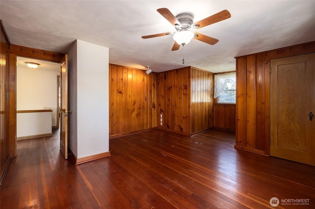 bonus room featuring wooden walls, baseboards, wood-type flooring, and a ceiling fan
