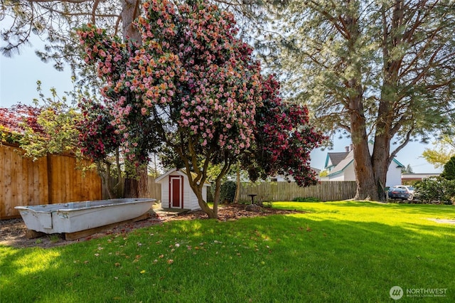 view of yard with a storage shed, an outbuilding, and a fenced backyard