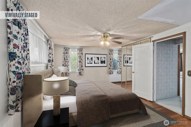 bedroom featuring wood finished floors, a textured ceiling, a ceiling fan, and ornamental molding
