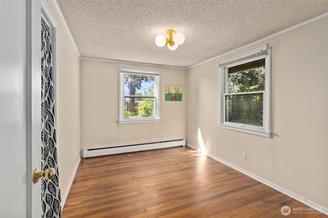 unfurnished room with baseboard heating, a textured ceiling, healthy amount of natural light, hardwood / wood-style floors, and ornamental molding