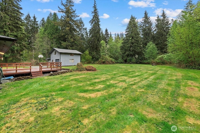 view of yard featuring a forest view and a wooden deck