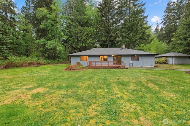 rear view of house with a yard, a wooden deck, and a chimney