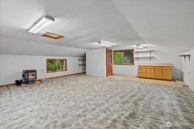 bonus room with attic access, light colored carpet, lofted ceiling, and a wood stove