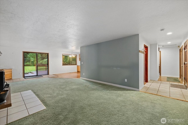 unfurnished living room with a textured ceiling, baseboards, and light colored carpet