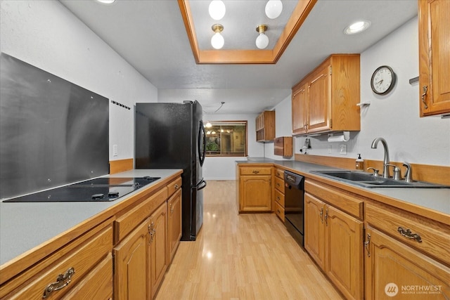 kitchen featuring a sink, brown cabinetry, black appliances, and light wood-style flooring