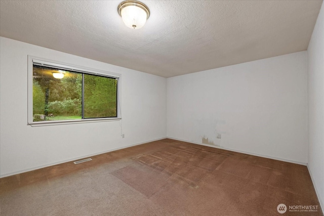 carpeted empty room featuring a textured ceiling, visible vents, and baseboards