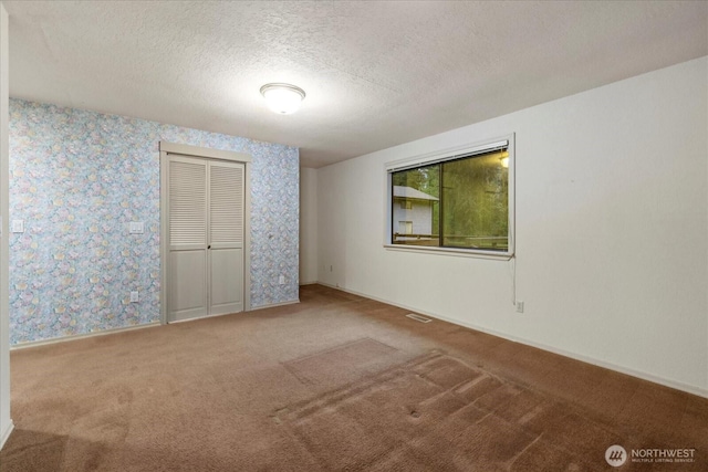 spare room with carpet flooring, a textured ceiling, and baseboards