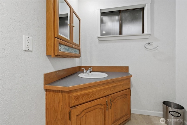 bathroom with vanity, baseboards, and a textured wall