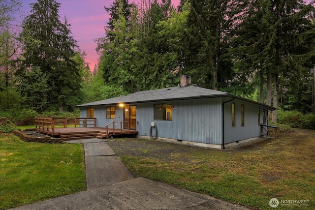 view of front of home featuring a lawn, a chimney, a wooden deck, and crawl space