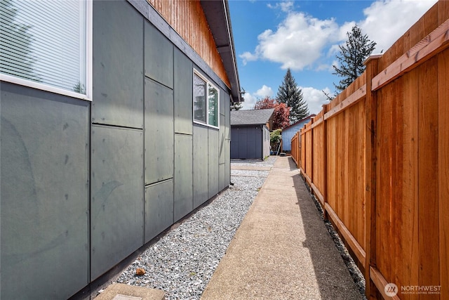 view of side of property featuring fence, a storage unit, and an outbuilding