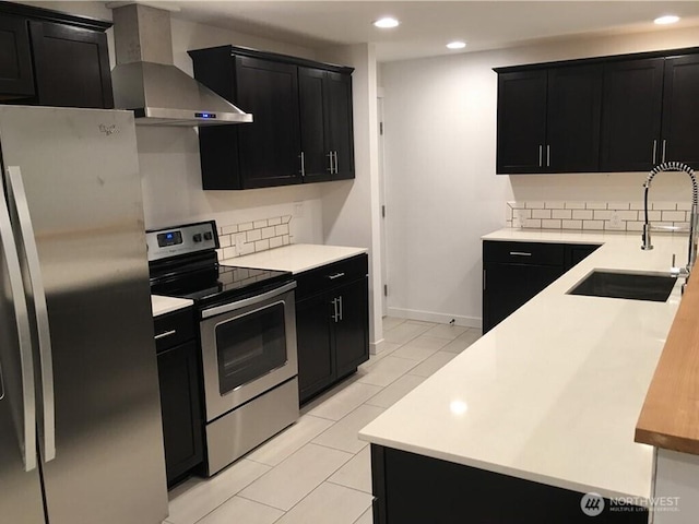 kitchen featuring dark cabinets, appliances with stainless steel finishes, and wall chimney exhaust hood