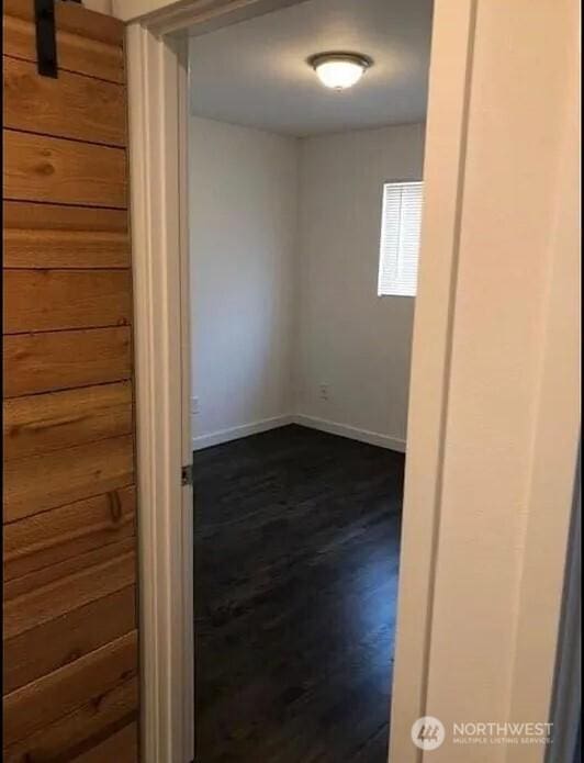 unfurnished room with baseboards and dark wood-style floors